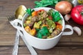 Served beef meat stewed with vegetables in ceramic pot with ingredients on wooden background Royalty Free Stock Photo