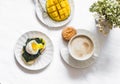 Served breakfast - cappuccino, fresh ripe mango, spinach sandwich with boiled egg on a light background, top view