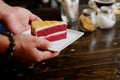 Served a piece of red velvet cake with two man hand with wooden dinning table background