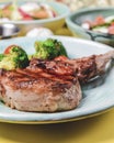 Served roast beef meat steak with brocoli cabbage and cherry toamtoes on a blue plate over bright yellow background