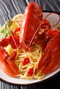 Served spaghetti pasta with red lobster, tomatoes, lemon and fresh herbs close-up on a black background. Vertical Royalty Free Stock Photo