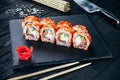 Served sushi rolls on black stone with chopsticks. Close up view on sushi on dark background. Royalty Free Stock Photo