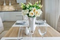 Served table with a bouquet of roses in interior of modern luxure guest room in studio apartments in minimalistic style