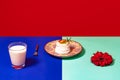 Served table. Food pop art photography. Glass of milk, cake and flower on blue and turquoise color tablecloth over red