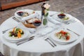 Served table for four with a bottle of wine, salads, glasses on the street waiting for guests