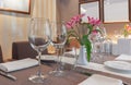 Served table in a restaurant with two empty glasses and orchids in a white vase