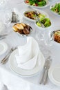 Served table seat in bright colors with a beautifully laid out napkin and salads in background