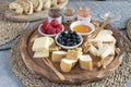 Served table - wine appetizer, cheese assortment on round wooden board, walnuts, berries, honey, jams, bread, copy space Royalty Free Stock Photo