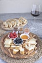 Served table - wine appetizer, cheese assortment on round wooden board, walnuts, berries, honey, jams, bread, red wine glass, copy Royalty Free Stock Photo