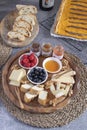 Served table - wine appetizer, cheese assortment on round wooden board, walnuts, berries, honey, jams, bread, red wine, savory Royalty Free Stock Photo