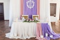 Served wedding banquet table in the restaurant decorated white, pink and purple material, white and pink flowers and greenery. Royalty Free Stock Photo