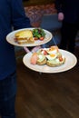 Server bringing out breakfast two dishes, Classic french toast with cheese and ham, and Avocado toast with soft boiled eggs Royalty Free Stock Photo