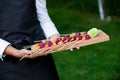 Server holding a wooden tray full of snacks during a catered event