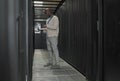 Server room, data center or IT black man with laptop for research, engineer working in dark server room. Computer