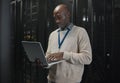 Server room, laptop and black man technician with data center management, system and cybersecurity. Focus, serious and