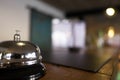 Service bell locating at reception. Silver call bell on table, receptionists on background