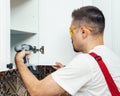 Service contractor using electric screwdriver while installing new furniture in kitchen