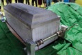 The service for the deceased was held in a cemetery. Before burial, the coffin was lowered into the ground on a conveyor