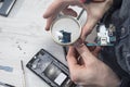 Service employee of mobile phones holds a magnifying glass in his hand and watches the mini usb plug through it.