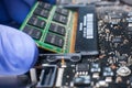 Service engineer install new RAM memory chips to the laptop. Repairing and upgrading laptop concept. Close up view