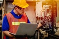 Service engineer team working with electronic wire back panel of heavy industry machine for maintenance repair and fix with laptop