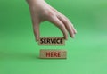 Service here symbol. Concept words Service here on wooden blocks. Beautiful green background. Businessman hand. Business and Royalty Free Stock Photo