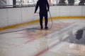 Service man pours water from a hose onto an ice rink. Ice preparation. Winter sport. Leisure on vacation