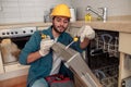 Focused handyman in special clothing repairing dishwasher in modern kitchen Royalty Free Stock Photo