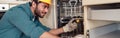 Focused handyman in special clothing repairing dishwasher in modern kitchen Royalty Free Stock Photo