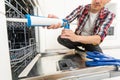 Service man repairing dishwasher in modern kitchen. Maintenance and household assistance concept Royalty Free Stock Photo