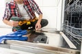 Service man repairing dishwasher in modern kitchen. Maintenance and household assistance concept Royalty Free Stock Photo