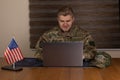 A service member is actively engaged in work on a laptop computer while seated Royalty Free Stock Photo