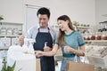 Asian male shopkeeper describe products to female customer in refill store