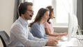 Side view call center employees working using computers and headsets