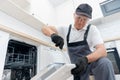 Service for repair and installation of dishwasher, male worker with tool in uniform
