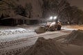 Service snow plowing truck cleaning residential street during heavy snowstorm, Toronto, Ontario, Canada.