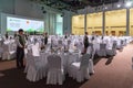 Service staff of Gorky Gorod resort ready to welcome guests standing still among round tables and chairs covered with white