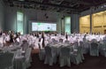 Service staff of Gorky Gorod resort ready to welcome guests standing still among round tables and chairs covered with white tablec