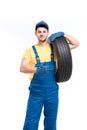 Service worker in blue uniform holds tire in hand Royalty Free Stock Photo