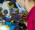 Service worker repairing mobile phone with microscope