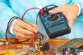 Serviceman checks electronic hardware with a multimeter in service workshop