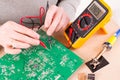 Serviceman checks PCB with a digital multimeter