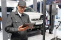 Serviceman with digital tablet on the background of the car in the car service..