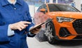 Serviceman with digital tablet on the background of the car in the car service