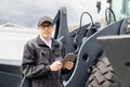 Serviceman with digital tablet on a background of the tractor