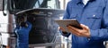 Serviceman with digital tablet on the background of the truck in the car service