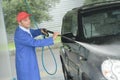 Serviceman with high pressure water jet washing car Royalty Free Stock Photo