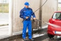 Serviceman With High Pressure Water Jet Washing Car Royalty Free Stock Photo