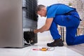 Serviceman In Overall Working On Fridge Royalty Free Stock Photo