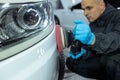 Serviceman polishing car body with machine in a workshop.